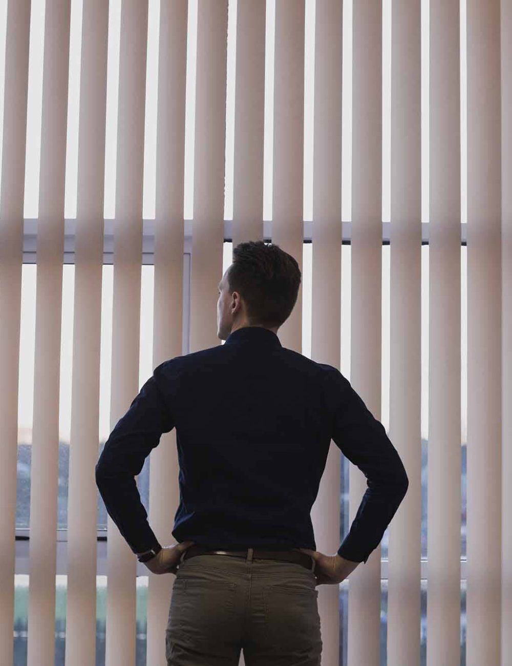 man-standing-with-hands-hip-near-window-blinds